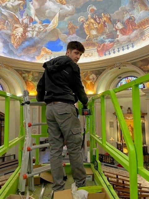 Operaio su trabattello sotto la cupola affrescata della chiesa