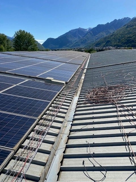Campo fotovoltaico su copertura industriale con le montagne della Valtellina sullo sfondo