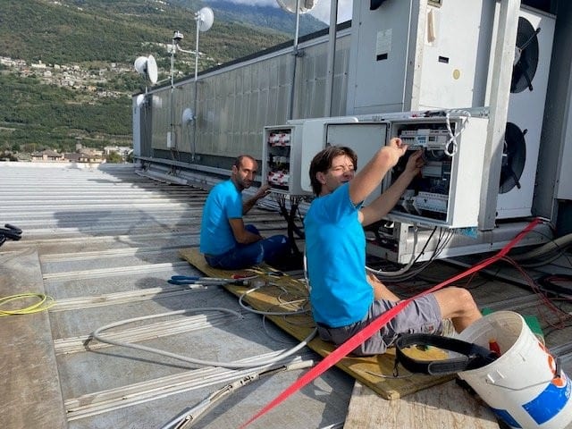 Due tecnici al lavoro su un quadro elettrico in copertura