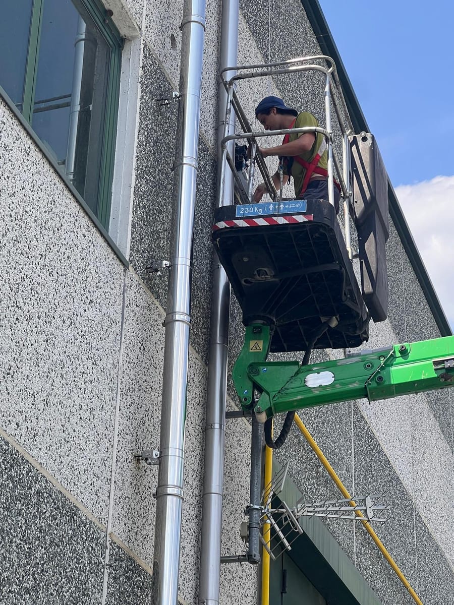 Tecnico su piattaforma aerea installa dispositivi sulla facciata di un edificio